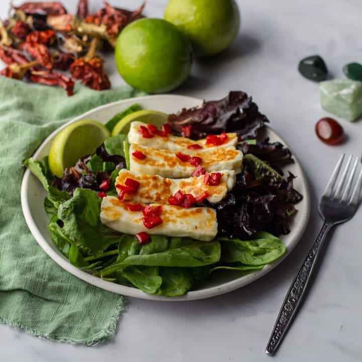 Fiery Halloumi Salad on white plate with green linen napkin and fork
